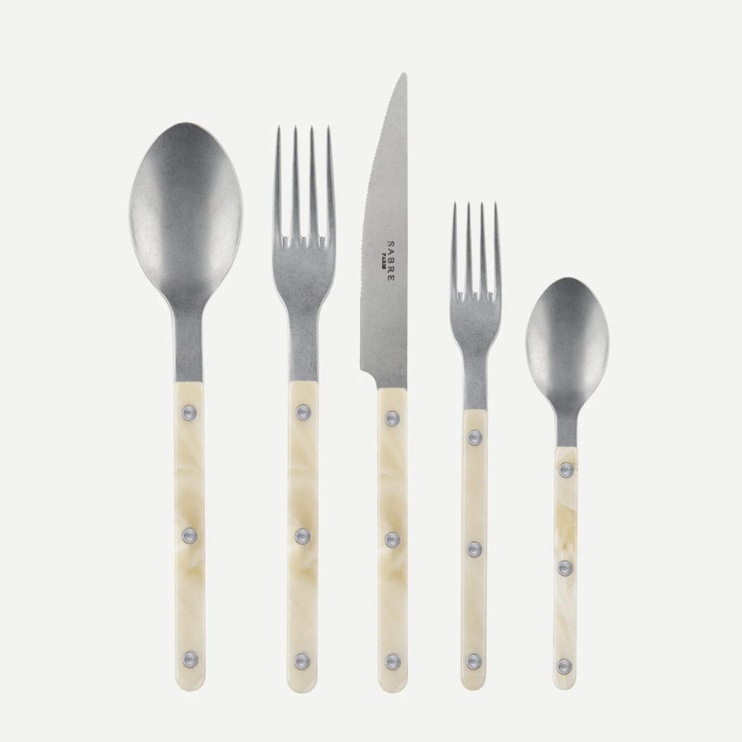The Sabre Bistrot Horn 5 Piece Place Setting includes a tablespoon, dinner fork, knife, salad fork, and teaspoon with cream-colored handles—made in France—displayed upright on a white background.