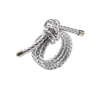 The Rope Knot Napkin Ring Set of 4 by Kim Seybert features metallic silver braided cords with metal-capped ends, intricately knotted in a circular design inspired by coastal style, shown on a plain white background.