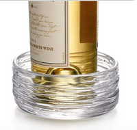 The Simon Pearce Echo Lake Wine Coaster is a clear, round glass dish with ribbed sides, inspired by Vermont craftsmanship, designed to hold a wine bottle from the Echo Lake Collection.