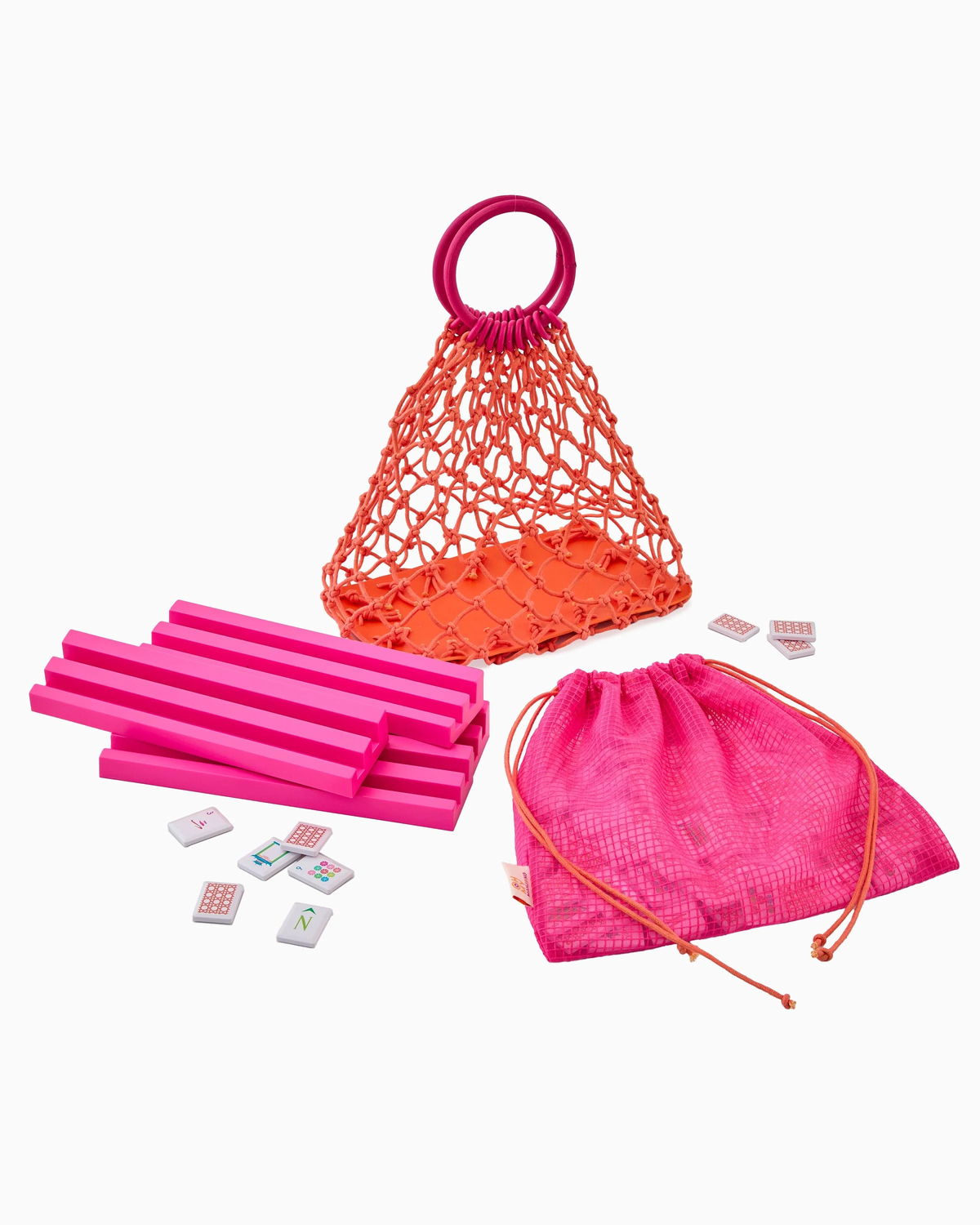 A pink mesh bag, a triangular orange net bag with a pink handle, pink rectangular blocks, and the Oh My Mahjong Mahjong Debutante Travel Tile Set are arranged on a white background.