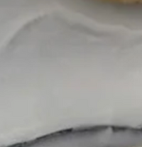 A close-up of a smooth, white frosted surface with gentle swirls, displayed on the Eye Candy Bagel Tray made from food safe silver marble acrylic.