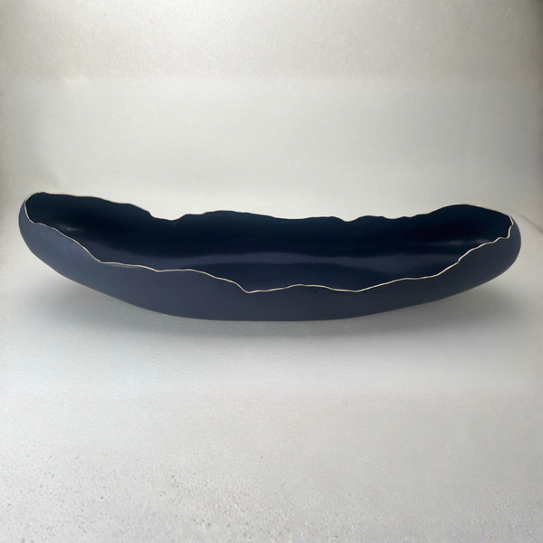 The Long Boat Bowl #1 - Black by Kate Tremel is a long, narrow black ceramic bowl featuring uneven, wavy edges outlined in white, displayed on a plain light background—perfect as a striking centerpiece or a unique serving bowl.