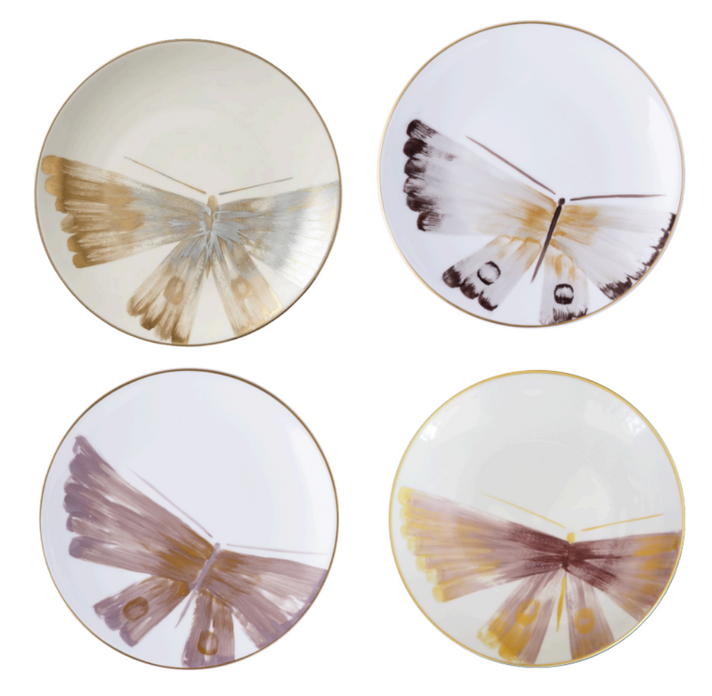 Four round plates by Marie Daâge, from the Belle De Nuit 1 collection, crafted from fine Limoges porcelain, feature a minimalist butterfly wing motif in gold, brown, and purple on white with thin gold rims.