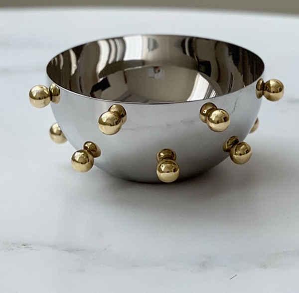 The Gold Balls Bowl - Small by BT-Shalom features a shiny silver finish with evenly spaced gold spherical knobs, displayed on a white marble surface.