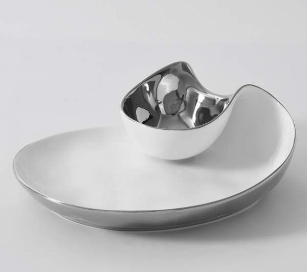 The PAMPA BAY Thin and Simple Chip & Dip is a modern, asymmetrical porcelain platter with a metallic silver rim and attached rounded silver bowl. Oven and dishwasher safe, both pieces have a sleek glossy finish.