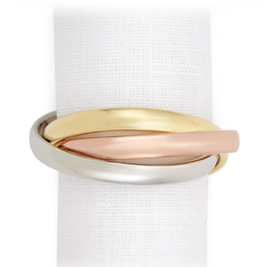 The Three Ring Jewel Napkin Set of 4 by L'Objet features intertwined gold, rose gold, and silver bands—24k gold plated and elegantly arranged on a white textured background. Presented in a luxury gift box.