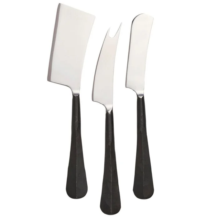 The Simon Pearce Woodbury Black Cheese Knife Set features three upright knives with black handles: one cleaver-shaped, one fork-tipped, and one flat rounded blade—each designed for cheese cutting.