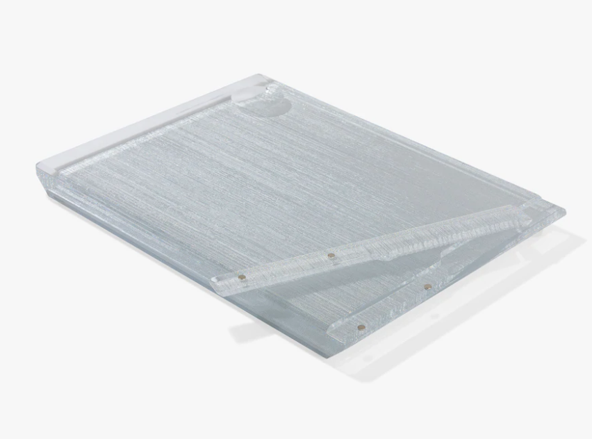 The Apeloig Personalized Solid Acrylic Challah Board, featuring a clear rectangular design with a hinged magnetic top flap and a small round cutout near the top edge, lies flat on a white background.