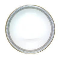 A white ceramic plate from Philippe Deshoulieres' Arcades Gold Dinnerware, with a gold and silver geometric rim, is shown from above against a plain background.