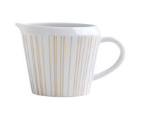 The Sol Dinnerware creamer by Bernardaud is crafted from white Limoges porcelain and features a handle, spout, and evenly spaced thin vertical gold lines around its body.