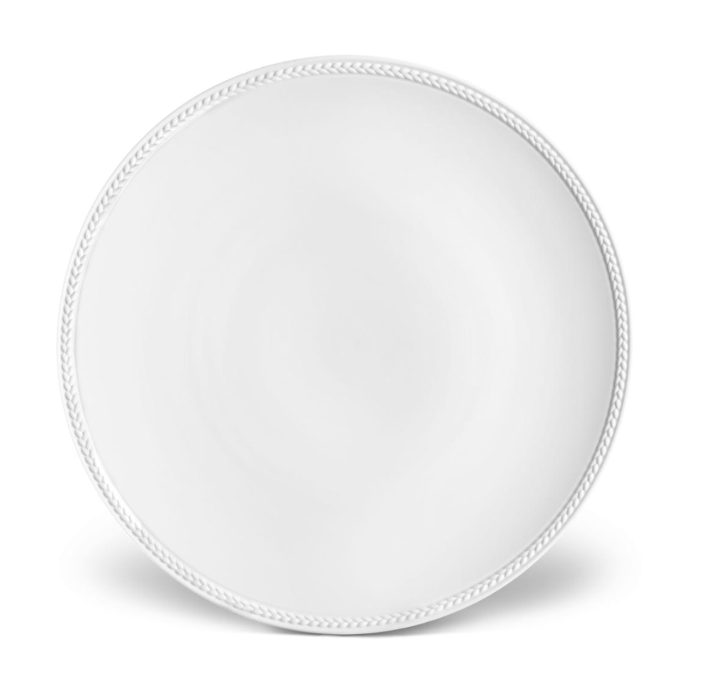 The Soie Tressée White Dinnerware plate by L'Objet is a round, white Limoges porcelain piece with a subtle braided rim pattern, displayed empty and well-lit on a plain white background to showcase its clean, elegant design.