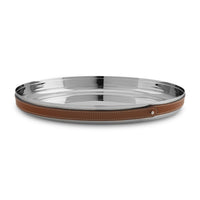 The Nambe Tahoe Bar Tray is a round, shiny stainless steel tray with a brown leather-wrapped rim, visible white stitching, and a metal stud accent, shown on a white background.