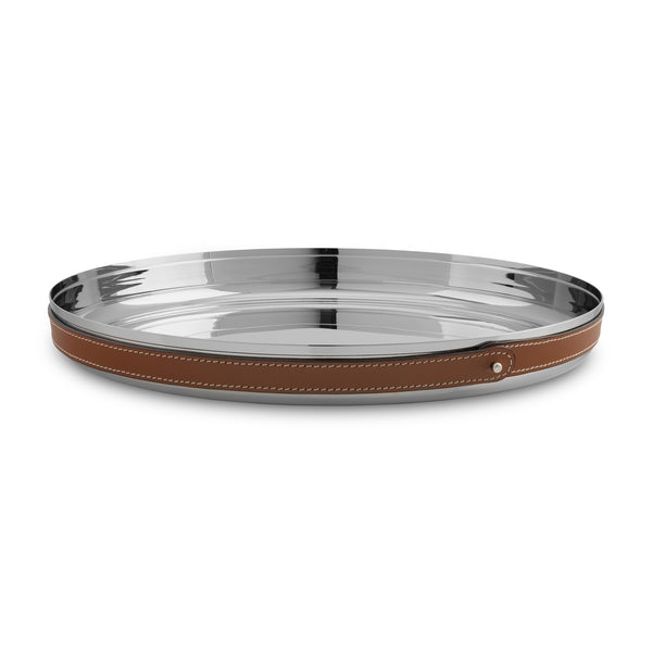 The Nambe Tahoe Bar Tray is a round, shiny stainless steel tray with a brown leather-wrapped rim, visible white stitching, and a metal stud accent, shown on a white background.