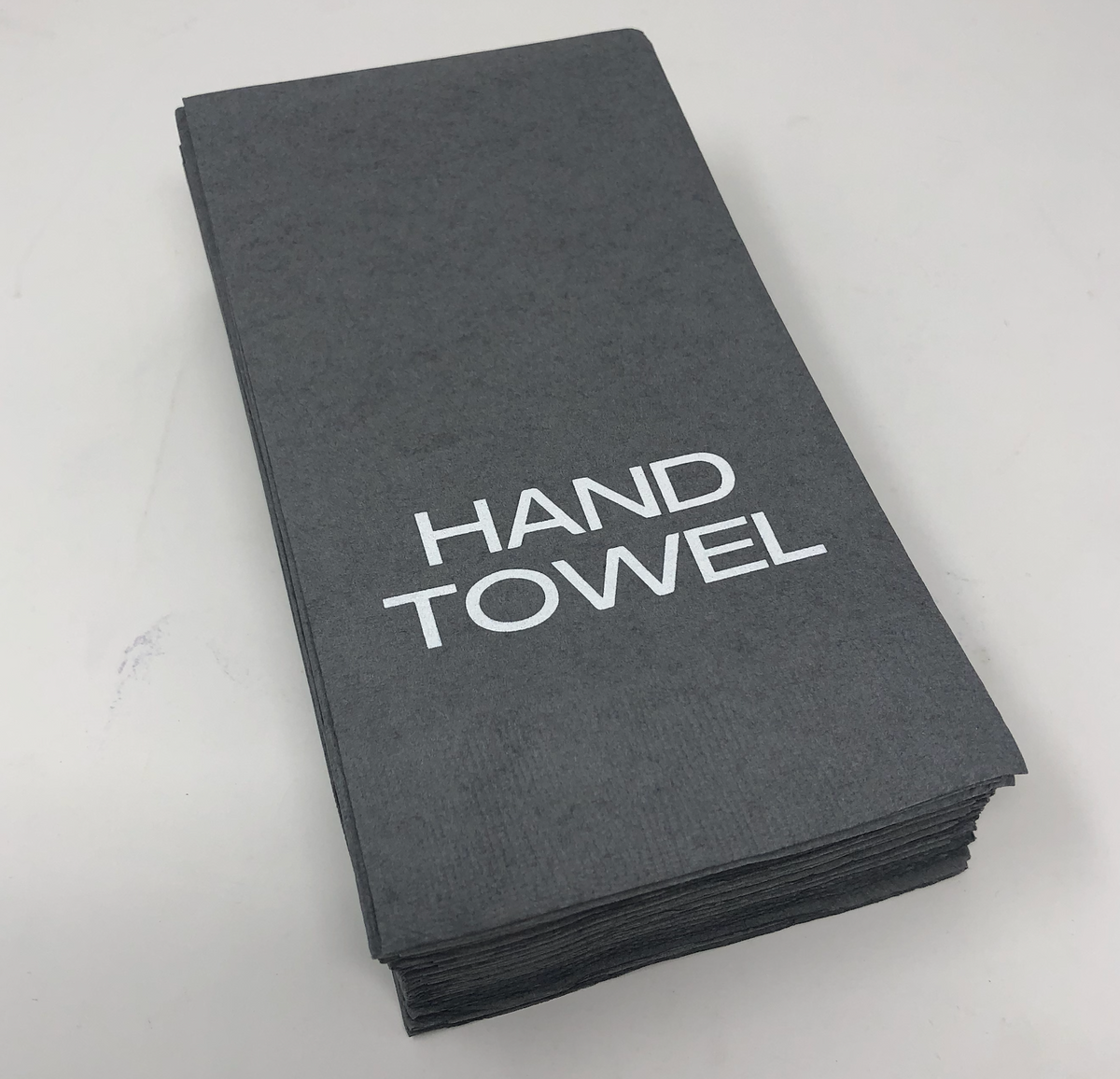 A stack of Print Appeal Guest Hand Towel Pack Pewter is displayed on a white surface, with the top towel featuring "HAND TOWEL" printed in large white letters.