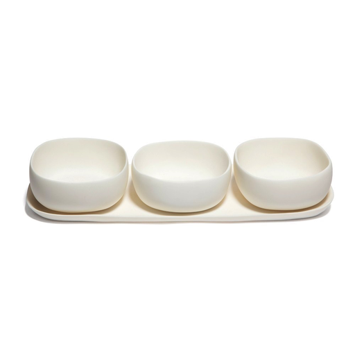 The Tina Frey Trio Of Bowls On Dish features three small, white, handmade resin bowls with a rounded square shape on a matching rectangular tray. All pieces are food-safe and crafted in San Francisco, shown against a clean white background.