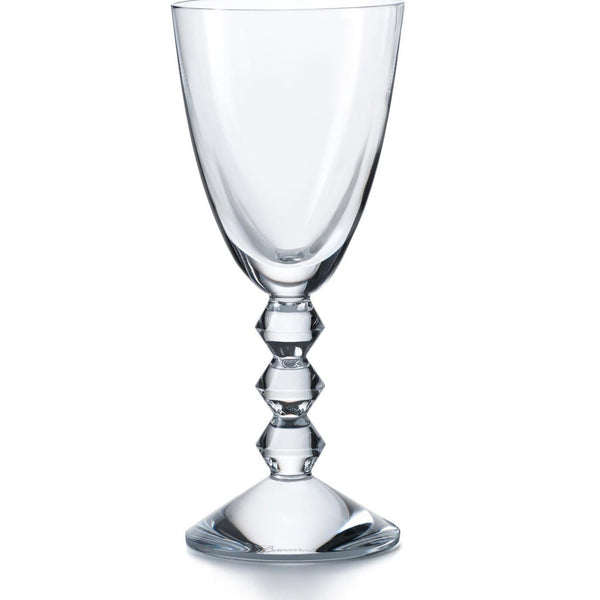 The Baccarat Vega White Wine Glass features a clear bowl and a distinctive stem with three geometric, diamond-shaped segments, set on a round base and shown against a plain white background.