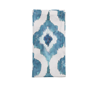 The Kim Seybert Watercolor Ikat Napkin Blue Set of 4 features folded white linen napkins with blue and teal diamond patterns, adding elegant abstract design to your table.