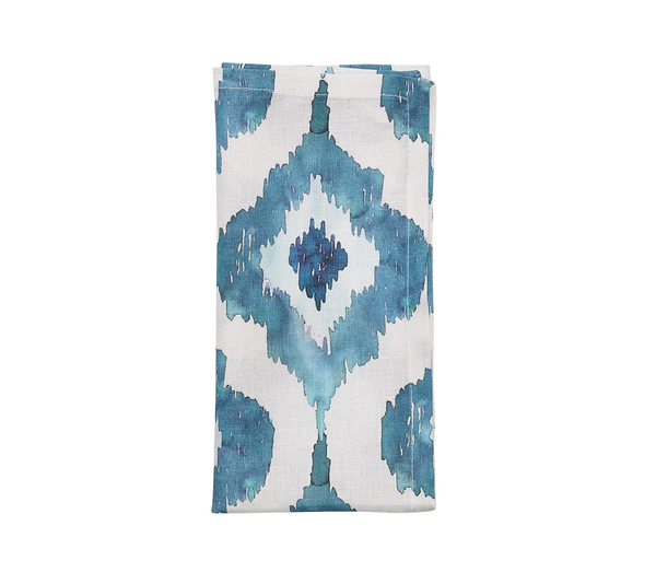 The Kim Seybert Watercolor Ikat Napkin Blue Set of 4 features folded white linen napkins with blue and teal diamond patterns, adding elegant abstract design to your table.