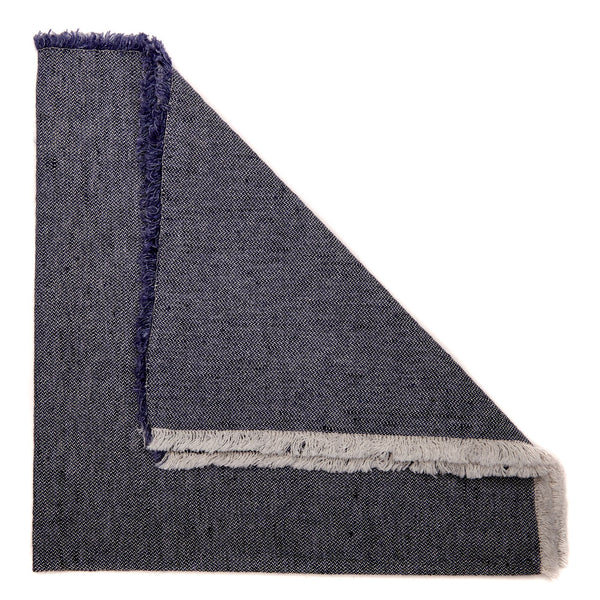 Folded navy napkin with frayed edges and woven texture, reminiscent of dark denim, from the Woven Washed Fringe Napkin Navy Set of 4 by Deborah Rhodes.