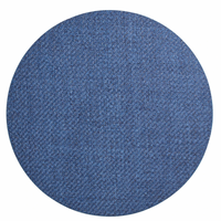 The Saigon Placemat Navy Set of 4 by Kim Seybert features circular blue denim placemats with a visible woven texture, inspired by Vietnamese plaiting technique, shown from above on a white background.