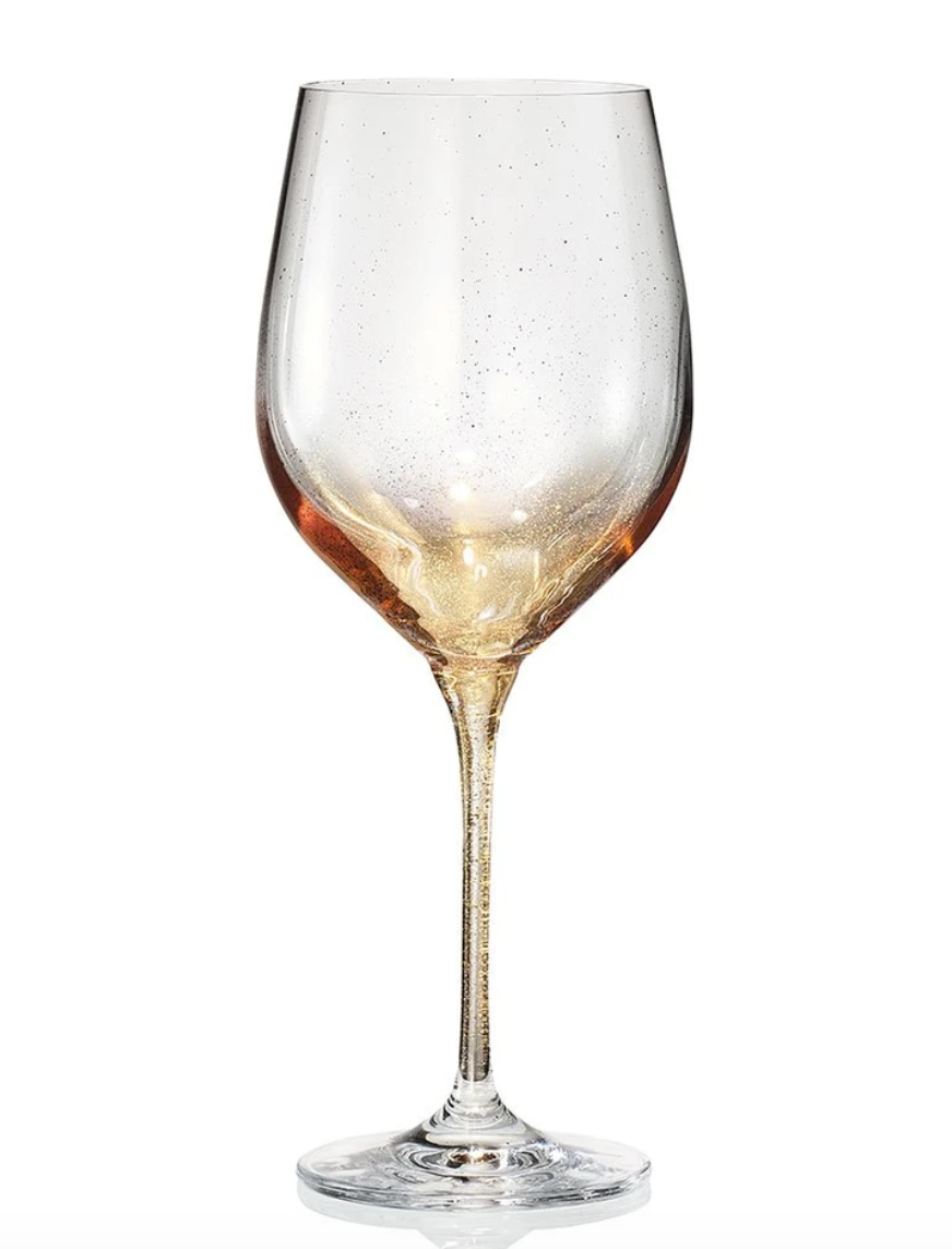 The Kim Seybert Orion Gold Barware Set of 4 features clear wine glasses with long stems, hand-sprayed gold at the bowl’s base, and a speckled texture throughout, showcased against a white background.