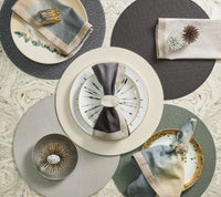 An elegant table setting features three plates, each with a folded napkin and decorative ring, arranged on Kim Seybert Shagreen Placemat Elephant Grey Set of 4 atop a marbled surface in neutral tones.
