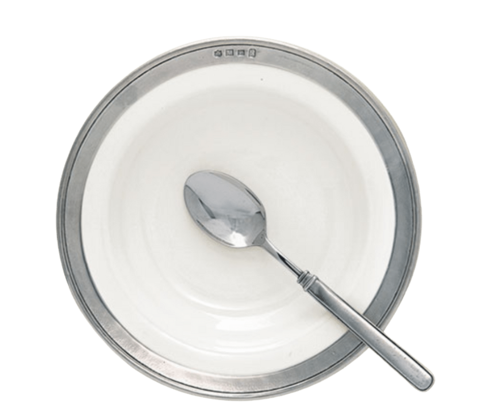 A round, white MATCH Convivio bowl with a metallic rim and hallmark symbols, viewed from above on a white background, holds a shiny metal spoon resting inside.