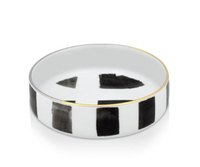 The Sol Y Sombra charger by Christian Lacroix x Vista Alegre is a round white porcelain piece with a thin gold rim and striking black abstract geometric shapes—an elegant dinnerware item from Vista Alegre.