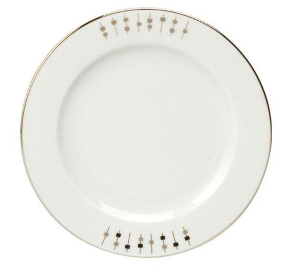 The Carrousel Dinnerware by Philippe Deshoulieres is a white Limoges porcelain plate with a thin gold rim and a minimalist border of gold lines and small squares, mainly decorating one side of the edge.