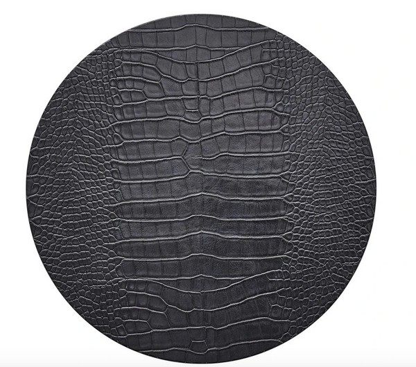 The Kim Seybert Croco Placemat Charcoal Set of 4 features a round, black surface with a textured, crocodile-embossed pattern resembling reptile skin, showcased against a white background.