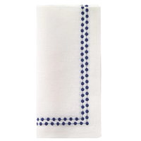 The Bodrum Pearls Napkin Navy Set of 4 features folded white linen napkins with a blue dotted embroidered border in an L-shaped design, adding elegance to any occasion.