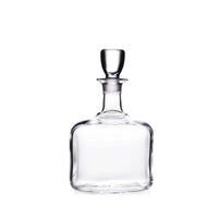 The Simon Pearce Woodbury Decanter features handblown glass, a round stopper, wide square base, and narrow neck—perfect for elevating your home bar. Shown on a white background.