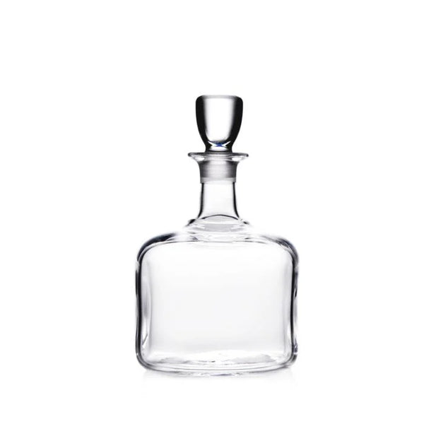 The Simon Pearce Woodbury Decanter features handblown glass, a round stopper, wide square base, and narrow neck—perfect for elevating your home bar. Shown on a white background.
