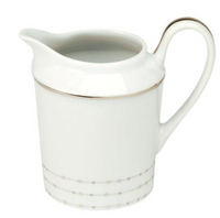 A white Carrousel Dinnerware milk or cream pitcher by Philippe Deshoulieres features platinum trim near the rim and base, a curved handle, spout, and a lower dotted line pattern inspired by their signature elegant design.