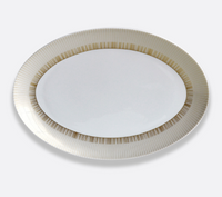 The Sol Dinnerware by Bernardaud is an oval white Limoges porcelain plate with a decorative gold-striped rim, shown from above against a plain light background.