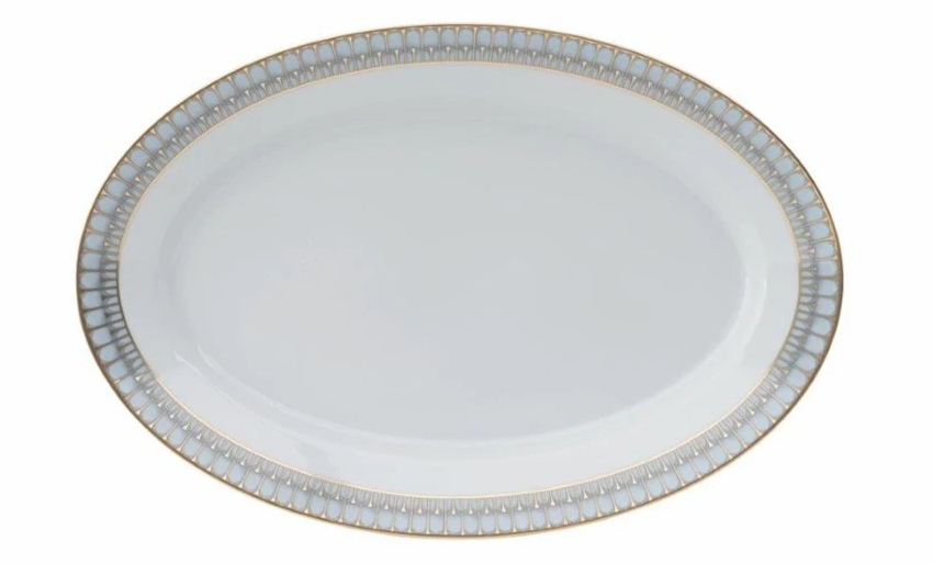 An empty porcelain oval plate from Philippe Deshoulieres Arcades Gold Dinnerware features a white center and a decorative rim with pale blue and gold accents.