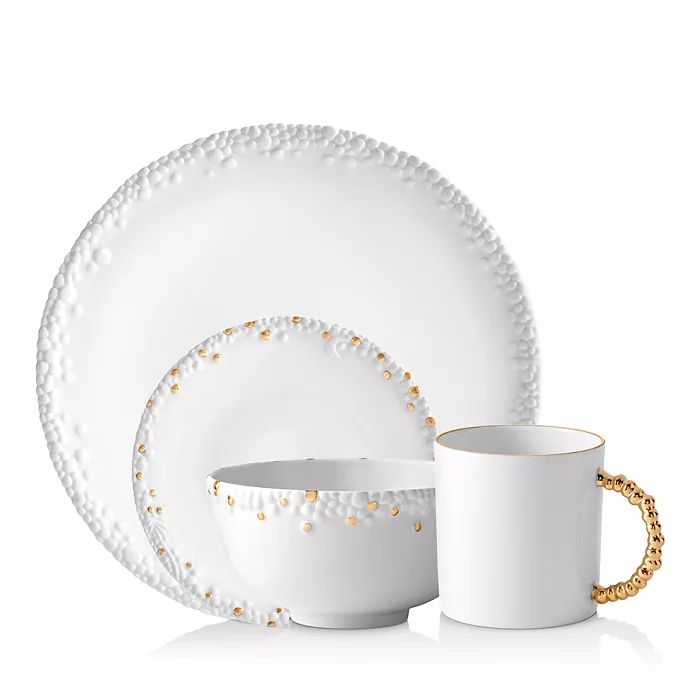 The Haas Mojave White Dinnerware by L'Objet features raised dot textures and gold accents on every piece, including a gold-beaded mug handle.