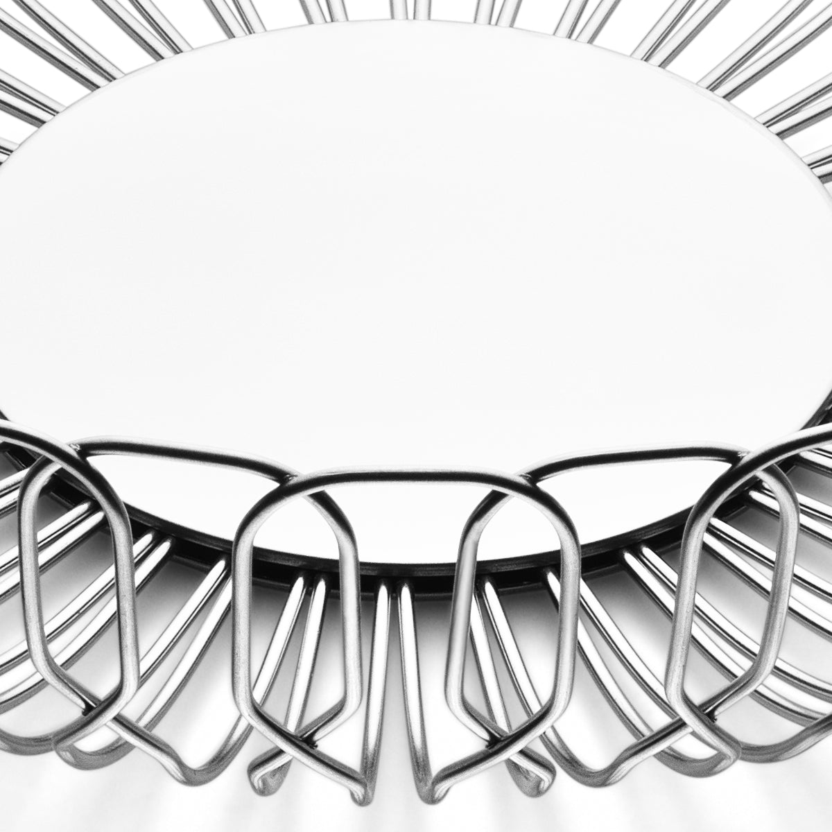 The Alfredo Bread Basket Large by Georg Jensen is a round, stainless steel wire fruit bowl with an open geometric design. Seen from above on a white background, its empty center makes it perfect for serving bread at dinner parties.