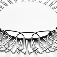 The Alfredo Bread Basket Large by Georg Jensen is a round, stainless steel wire fruit bowl with an open geometric design. Seen from above on a white background, its empty center makes it perfect for serving bread at dinner parties.