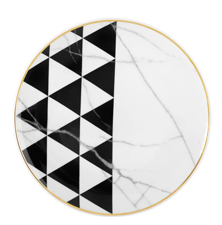 The Carrara by Coline Le Corréa Dinnerware from Vista Alegre features a round porcelain plate with a gold rim, white Carrara marble pattern, and black and white geometric triangles reflecting French designer elegance.