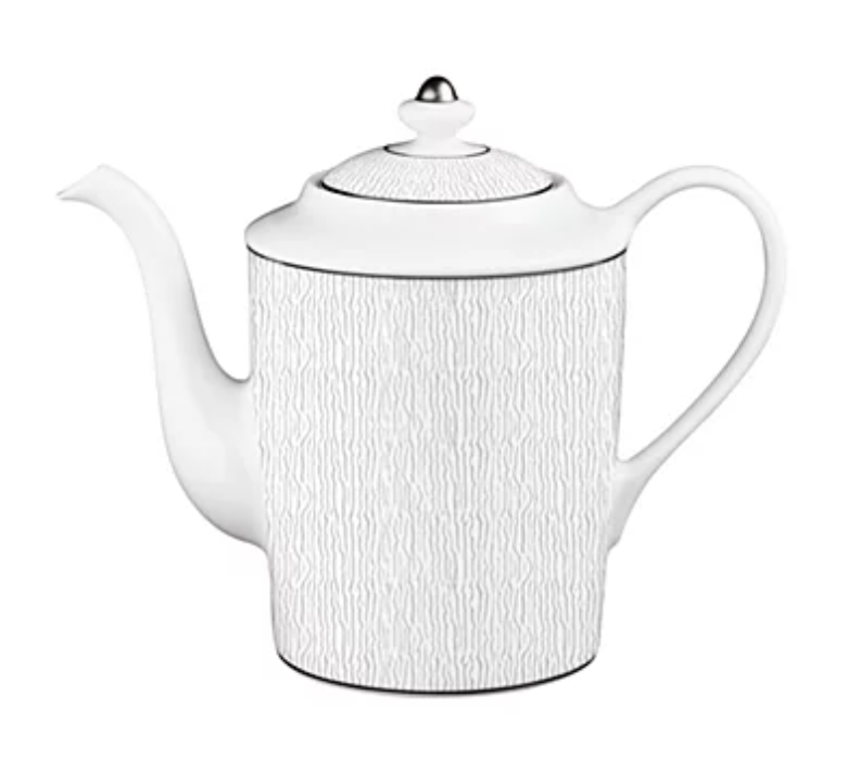 A white Limoges porcelain teapot featuring vertical lines, a curved spout, looped handle, and a silver-knobbed lid pairs perfectly with Bernardaud’s Dune Dinnerware.