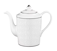 A white Limoges porcelain teapot featuring vertical lines, a curved spout, looped handle, and a silver-knobbed lid pairs perfectly with Bernardaud’s Dune Dinnerware.