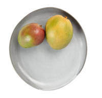 Two mangoes—one smaller, red-green and one larger, yellow-green—rest on a Marcus Cement Dinnerware plate by Blue Pheasant against a white background.