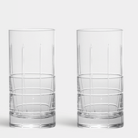 The Orrefors Kosta Boda Street Highball Glass Set of 2 features tall, clear glasses with vertical ribbing on the upper half and a grid pattern at the base.