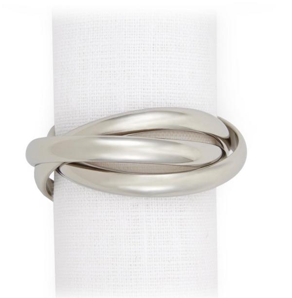 A white textured napkin is vertically displayed against a white background, wrapped with a silver-tone Three Ring Jewel Napkin ring from L'Objet’s Napkin Set of 4.