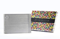 The Apeloig Collection Metallic Silver Acrylic Challah Board sits beside a colorful geometric-patterned box, making an elegant gift for any occasion.