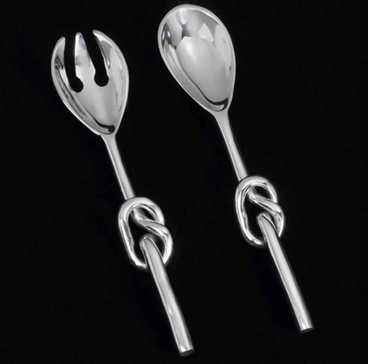 The Knotty Salad Set by Inspired Generations features a fork and spoon, each handcrafted from polished aluminum with twisted knot handles, beautifully displayed on a black background.