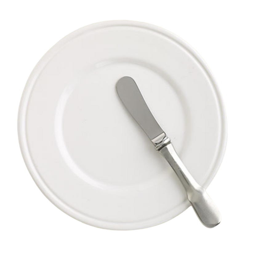 A MATCH Convivio butter plate in white is paired with a silver butter knife, resting diagonally atop it on a plain background, highlighting the timeless elegance of MATCH Italian ceramic dinnerware.