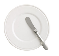 A MATCH Convivio butter plate in white is paired with a silver butter knife, resting diagonally atop it on a plain background, highlighting the timeless elegance of MATCH Italian ceramic dinnerware.