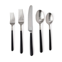 The Simon Pearce Hampton Flatware 5 Piece Setting includes two forks, a knife, a tablespoon, and a teaspoon with black resin handles and stainless steel, shown side by side on a white background.